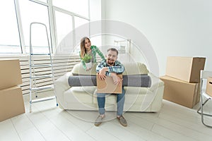 Cheerful young couple rejoices in moving to a new home laying out their belongings in the living room. Concept of