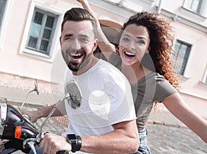 Cheerful young couple riding a scooter and having fun