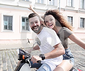 Cheerful young couple riding a scooter and having fun