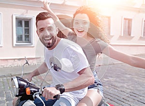 Cheerful young couple riding a scooter and having fun