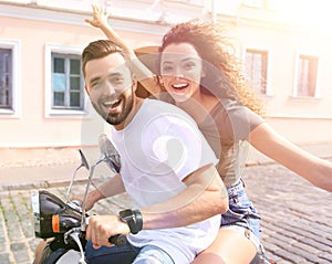 Cheerful young couple riding a scooter and having fun