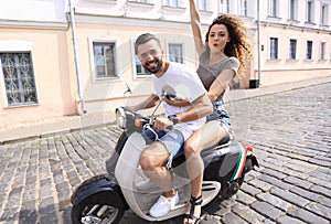 Cheerful young couple riding a scooter and having fun
