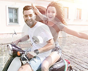 Cheerful young couple riding a scooter and having fun