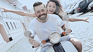 Cheerful young couple riding a scooter and having fun