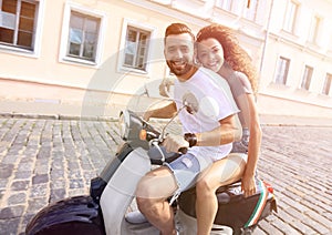 Cheerful young couple riding a scooter and having fun