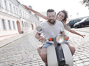 Cheerful young couple riding a scooter and having fun