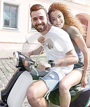 Cheerful young couple riding a scooter and having fun