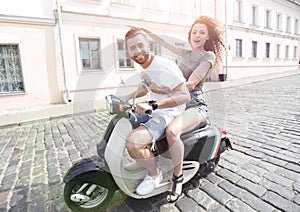 Cheerful young couple riding a scooter and having fun