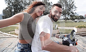 Cheerful young couple riding a scooter and having fun