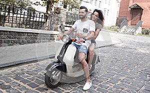 Cheerful young couple riding a scooter and having fun