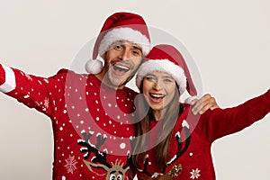 Cheerful Young Couple In Santa Hats And Christmas Sweaters Taking Selfie Together