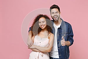 Cheerful young couple two friends european guy african american girl in casual clothes isolated on pastel pink wall