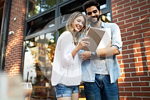 Cheerful happy couple using digital tablet outdoors