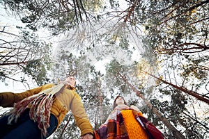 Cheerful young couple walking in the winter forest, low angle