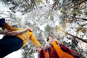 Cheerful young couple walking in the winter forest, low angle