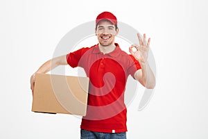 Cheerful young delivery man showing okay gesture.
