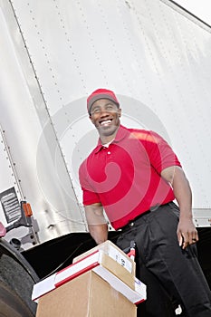 Cheerful young delivery person pushing handtruck photo