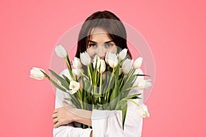 Cheerful young european lady smelling bouquet of flowers, enjoy lifestyle, aroma of tulips, rejoice spring