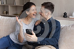 Cheerful young family couple celebrating getting online lottery win notification.