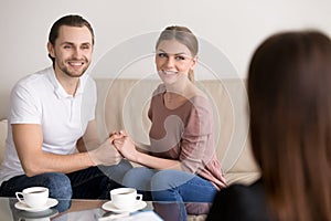 Cheerful young family couple on consultation. Holding hands and