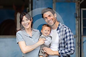 cheerful young family spending time together at farm