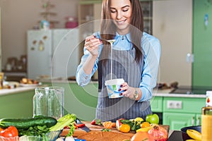 Cheerful young female chef cooking dessert adding condensed milk in dish in her kitchen