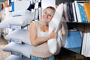 Cheerful young female holding cotton pillow