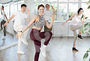 Cheerful young female instructor leading zumba class