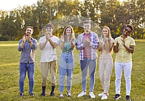 Cheerful young female and male friends applaud together during summer walk in park.