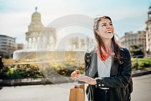 Cheerful young female tourist shopping on Catalonia SquarePlaca de Catalunya,La Rambla street,Barcelona,Spain.Best shopping