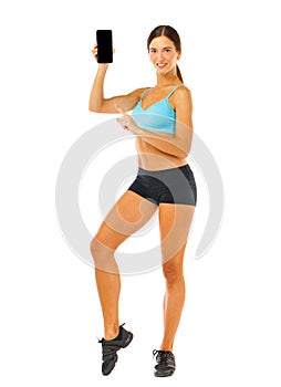 Cheerful young fitness woman showing blank smartphone screen isolated over white background