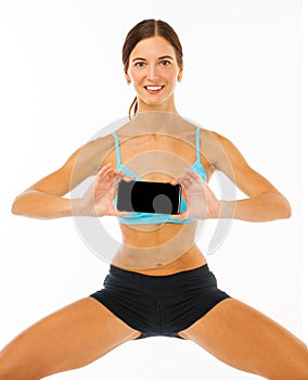 Cheerful young fitness woman showing blank smartphone screen isolated over white background