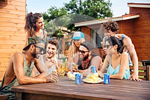 Cheerful young friends drinking beer outdoor summer party