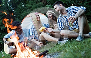 Cheerful young friends having fun by campfire