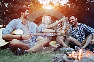 Cheerful young friends having fun by campfire