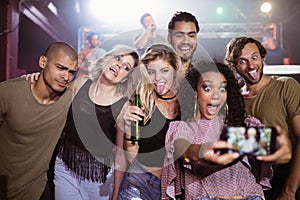 Cheerful young friends talking selfie at nightclub