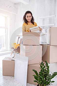 Cheerful young girl packing books and smiling