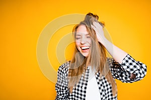 Cheerful young girl rejoices, rubbing her hair with her hands, laughing and closing her eyes