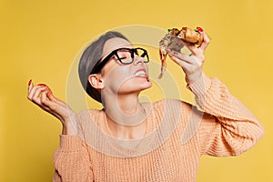 Cheerful young girl tasting delicious Italian pizza isolated on yellow studio background. World pizza day