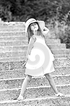 Cheerful young girl in white dress and straw hat