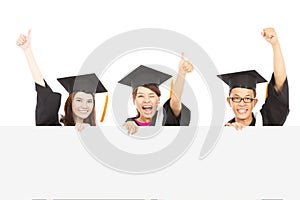 Cheerful young graduate students raise hands