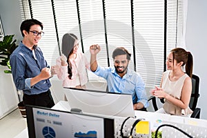 The cheerful young group of Asian businessmen in casual with Indian one raised hand with success emotion and colleagues happy