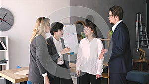 Cheerful young group of people discuss something in the office and giving high five