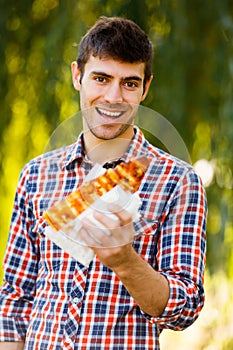 Cheerful young guy is eating pizza on the park
