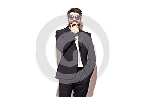 Cheerful young handsome man in sunglasses keeping hand on chin
