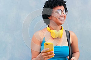 Cheerful young Hispanic girl holding phone outdoors