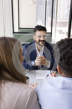 Cheerful young Indian consultant man meeting with couple