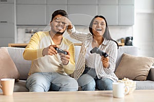 Cheerful Young Indian Couple Having Fun At Home, Playing Video Games Together