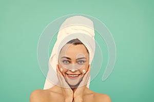 cheerful young lady applying face cream on blue background