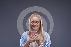 Cheerful young lady in blue shirt using cellphone